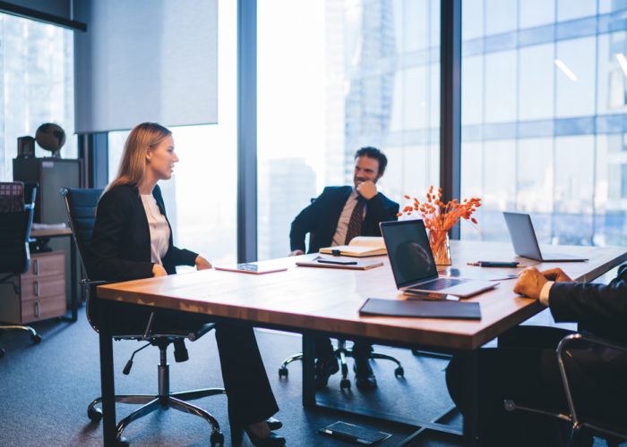 Successful professional experts in elegant wear discussing productive plan for work of employees during business meeting in conference room, concept of corporate brainstorming and collaboration